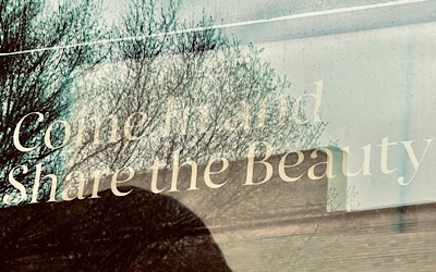 Lettering on store window reads:  “Come in and share the beauty.”