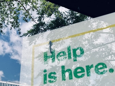 Sign in store window, reads”help is here.”