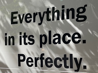 Sign in store window, reads”” “everything in its place. Perfectly.”