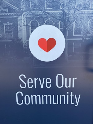 Sign with red heart in a white circle and the words, “serve our community.”