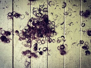 Photo of cut, curly dark hair in a pile on the floor 
