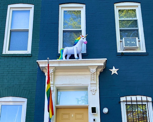 Photo of Capitol Hill row house with a rainbow flag at the door and a rainbow unicorn over the door 