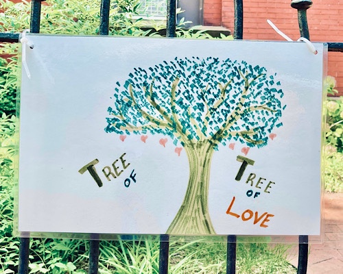 Drawing attached to a fence of a tree that says, “tree of/tree of love”