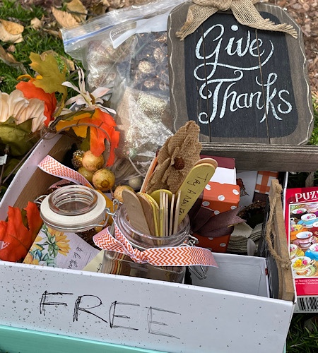 Box of discarded items with a “free” sign includes a plaque reading, “give thanks.”