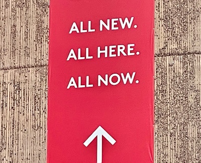 Sign reads, “All new.  All here.  All now.”
