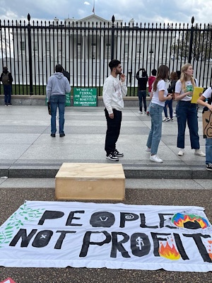 Sign in foreground reads “People Not Profit.”  Sign propped against White House fence reads:  “we need a federal job guarantee with benefits.  End unemployment.”