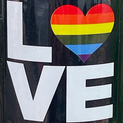 Pride sticker reads, “LOVE” with the “O” represented by a rainbow colored heart.