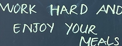 “Work hard and enjoy your meals,” written on sign in front of restaurant 