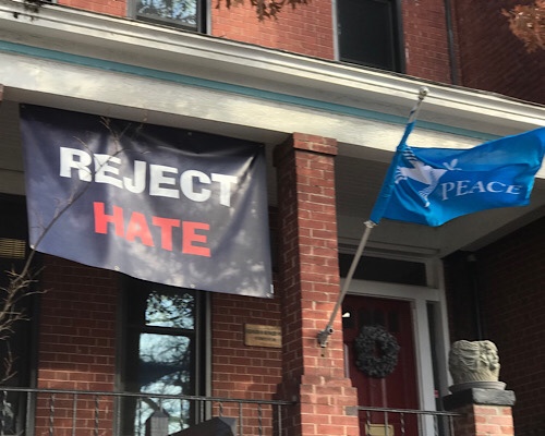 Banner reads “reject hate” and flag reads “peace.”