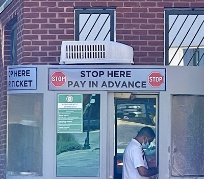 Sign over kiosk in parking lot reads, “Stop here.  Pay in advance.”