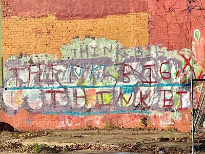 Photo of graffiti on brick wall that says, think big, think big, think big.