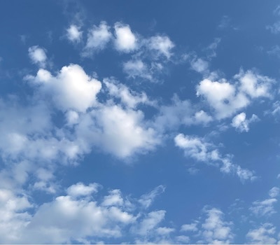 Fluffy white clouds, a couple heart-shaped, against a blue sky 
