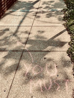 Chalk drawing on sidewalk from bottom to top reads, “you must hop, skip, dance