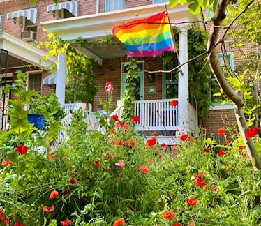 Photo of row house with poppies in the garden and a rainbow pride flag