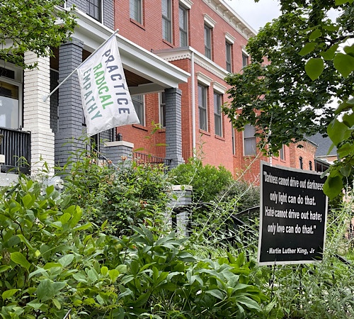 Image of row house with flag that reads “practice radical empathy”