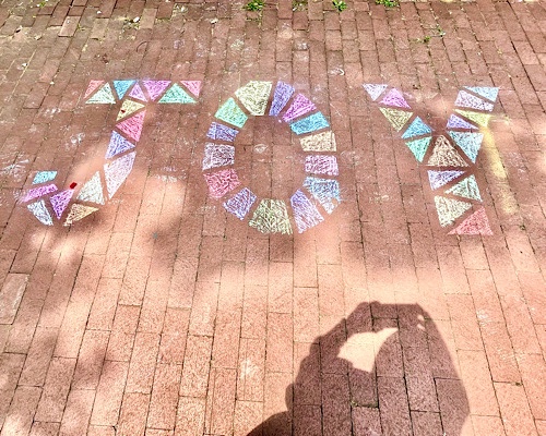 Chalk drawing of word “joy” on brick sidewalk 